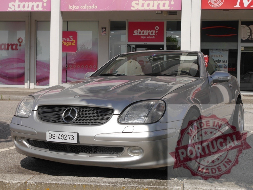 Mercedes-Benz SLK-Class roadster parked at storefront | Silver Mercedes-Benz SLK-Class roadster parked in front of a shopping center - Realized with Pictrs.com