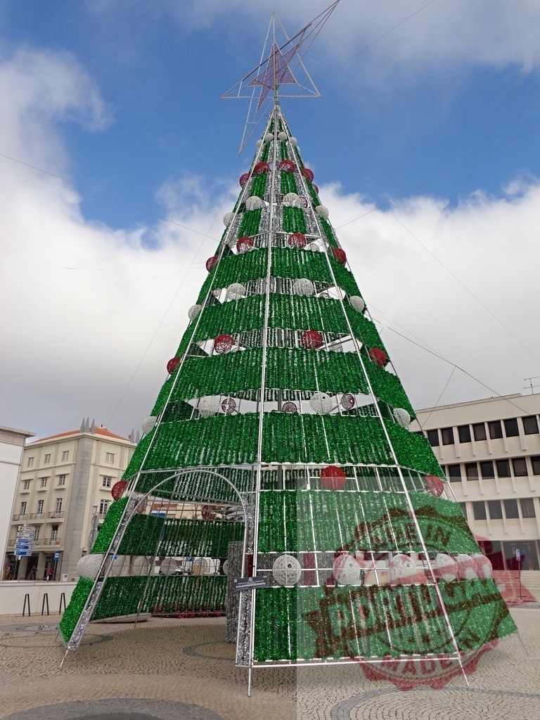 Large modern christmas tree standing tall in city square | Modern green and white artificial christmas tree with red and white ornaments in a city square - Realisiert mit Pictrs.com