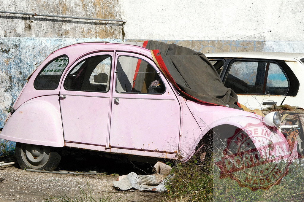 Vintage pink Citroen 2CV abandoned in urban setting | Classic French Citroen 2CV in deteriorating condition stands neglected against weathered wall - Realized with Pictrs.com