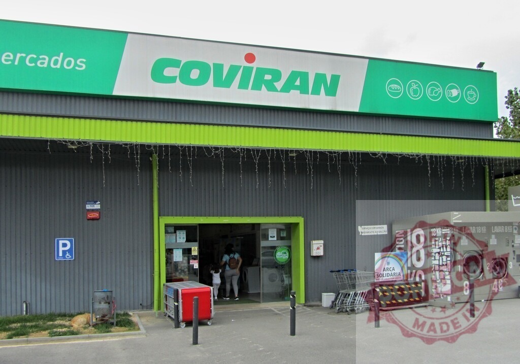 Coviran supermarket exterior with self-service laundromat | Coviran grocery store facade featuring a self-service washing machine area and shopping carts - Realized with Pictrs.com