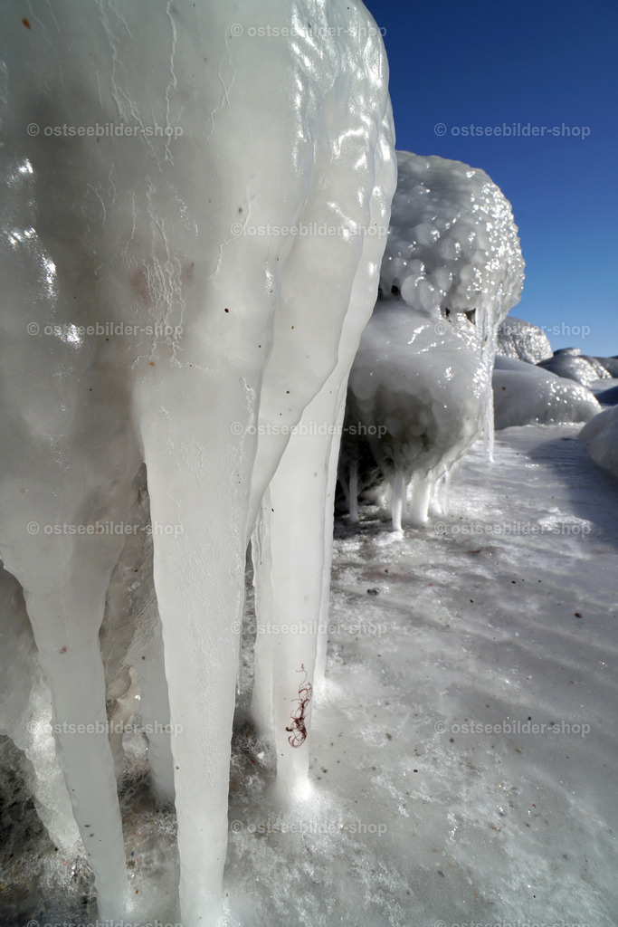 Unter Eisschichten und Eiszapfen verborgene Steine am Ostseestrandd | Brandung und feine Gischt hüllen Findlinge in einen Mantel aus Eis.