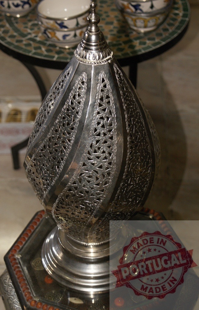 Moroccan silver lamp with intricate metalwork design | Ornate Moroccan lantern with filigree metalwork sitting on a decorative table - Realized with Pictrs.com
