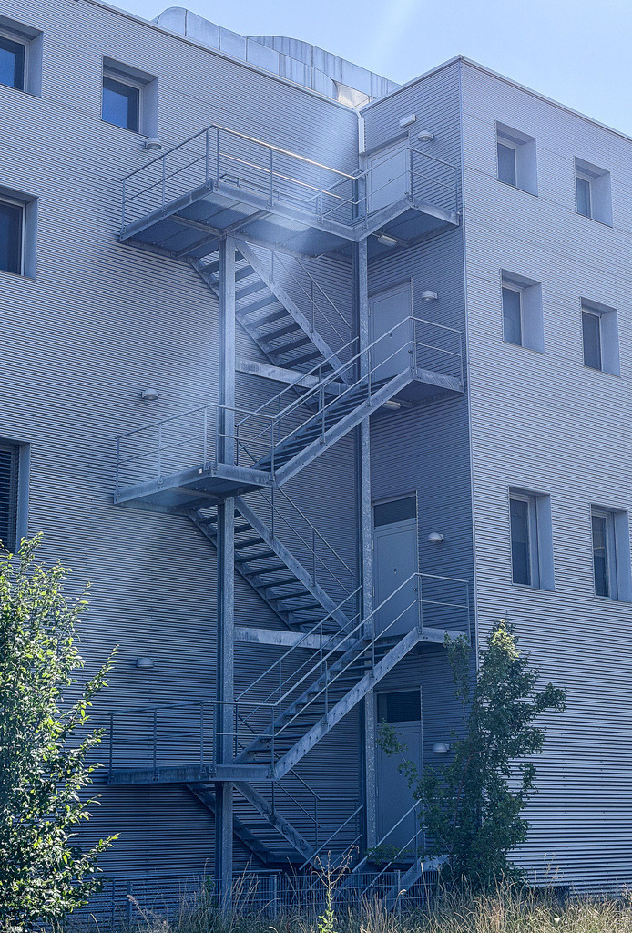Urban Geometry – Muttenz I | Moderne Architekturfotografie aus der Region Basel. Dieses minimalistische Kunstwerk fängt das faszinierende Zusammenspiel von Sichtbeton, markanten Stahltreppen und dramatischem Lichteinfall nahe dem Bahnhof Muttenz ein. Perfekt als hochwertiges Wandbild für moderne Büros, Lofts und stilbewusste Wohnräume. - Realisiert mit Pictrs.com