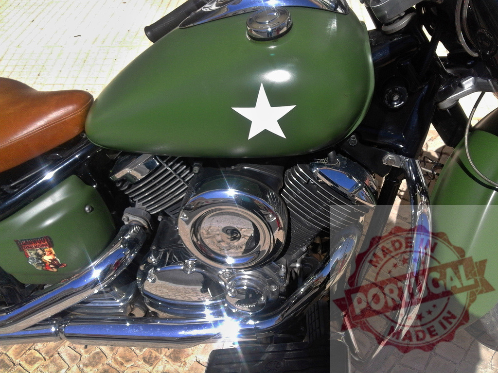 Green military style cruiser motorcycle with chrome engine | Green cruiser motorcycle with a white star decal, chrome engine, and brown leather seat - Realized with Pictrs.com