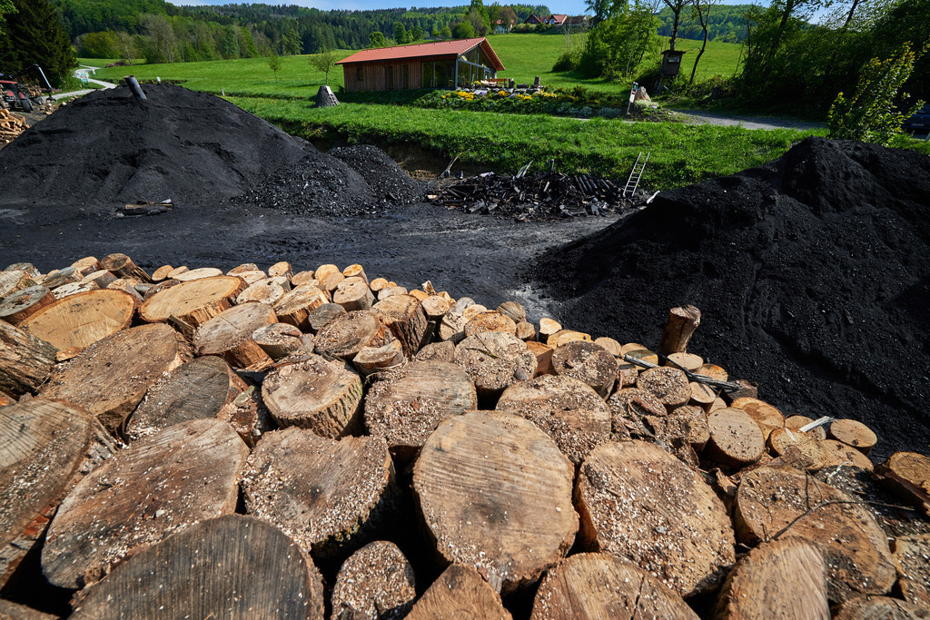 Blick vom Kohlmeiler auf den Köhlerplatz und das Köhlerhaus | Michelbach, Austria - May 08, 2019: Waldköhlerei Hochecker, die 2011 in das Nationale Verzeichnis des immateriellen Kulturerbes der UNESCO aufgenommen wurde, produziert noch echte Holzkohle; Blick vom Kohlmeiler auf den Köhlerplatz und das Köhlerhaus. - Realisiert mit Pictrs.com