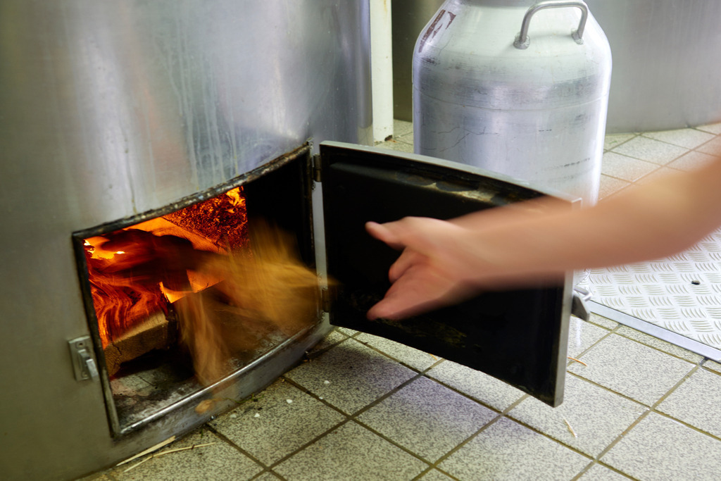 n die Feuerstelle wird Holz nachgelegt | Laterns, Austria - July 28, 2017: In die Feuerstelle wird Holz nachgelegt. - Realisiert mit Pictrs.com