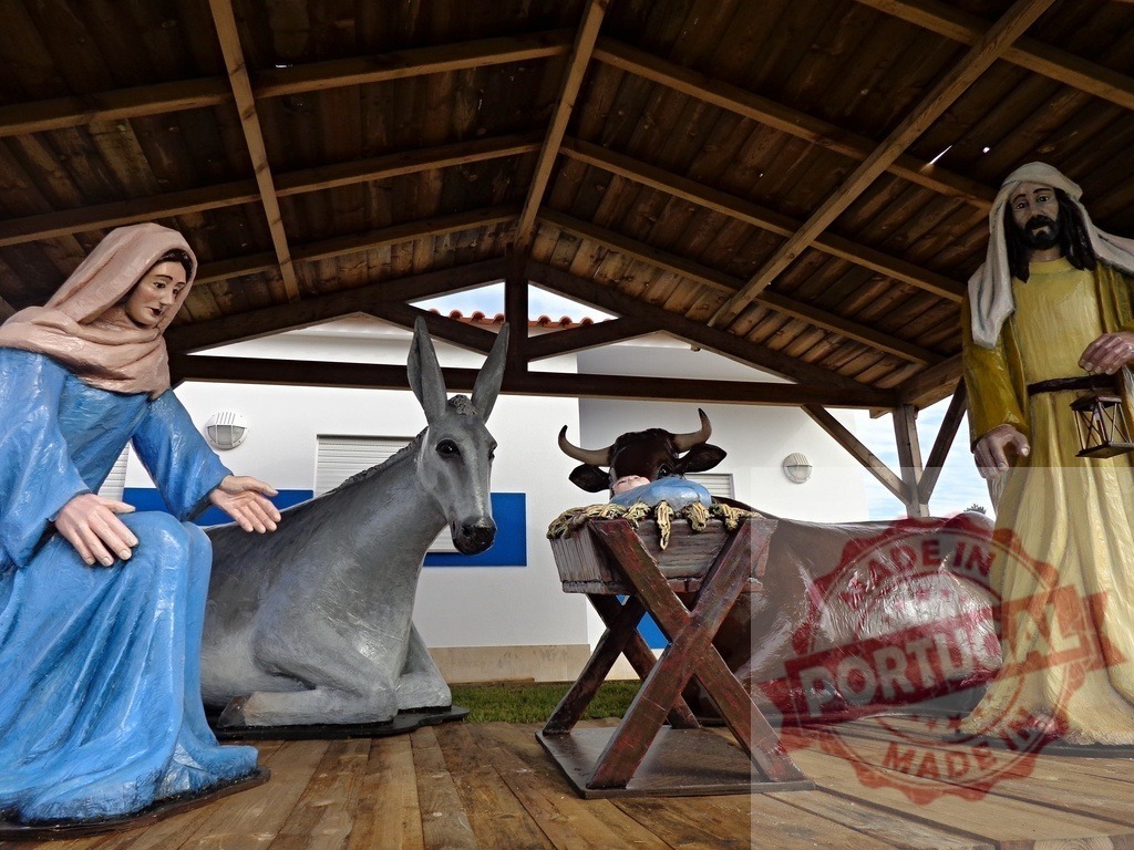 Nativity scene representing the birth of Jesus with Mary, Joseph, ox and donkey looking at baby Jesus | Nativity scene with statues of Mary, Joseph, ox, donkey and baby Jesus in a manger under a wooden roof - Realized with Pictrs.com