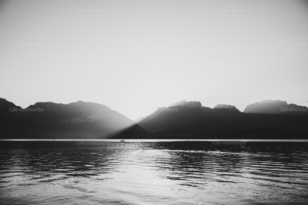 Ruhe | „Ruhe“ ist ein eindrucksvolles Naturfotografie-Kunstwerk, das die stille Schönheit eines unberührten Bergsees einfängt. Im Mittelpunkt des Bildes liegt ein kleines Anglerboot, sanft auf der spiegelglatten Wasseroberfläche treibend. Dahinter erheben sich majestiche Alpenfelsen, durch die die warmen Sonnenstrahlen des Sonnenaufgangs strahlen – ein Moment voll Harmonie, Klarheit und natürlicher Erhabenheit.Dieses Bild vereint die Sanftheit des Morgens mit der Kraft der Berge und schafft damit eine Atmosphäre, die ideal für Wohnräume, Büros, Hotels oder Wellnessbereiche ist. „Ruhe“ lädt den Betrachter ein, tief durchzuatmen, im Moment anzukommen und die Stille der Natur zu spüren. - Realisiert mit Pictrs.com