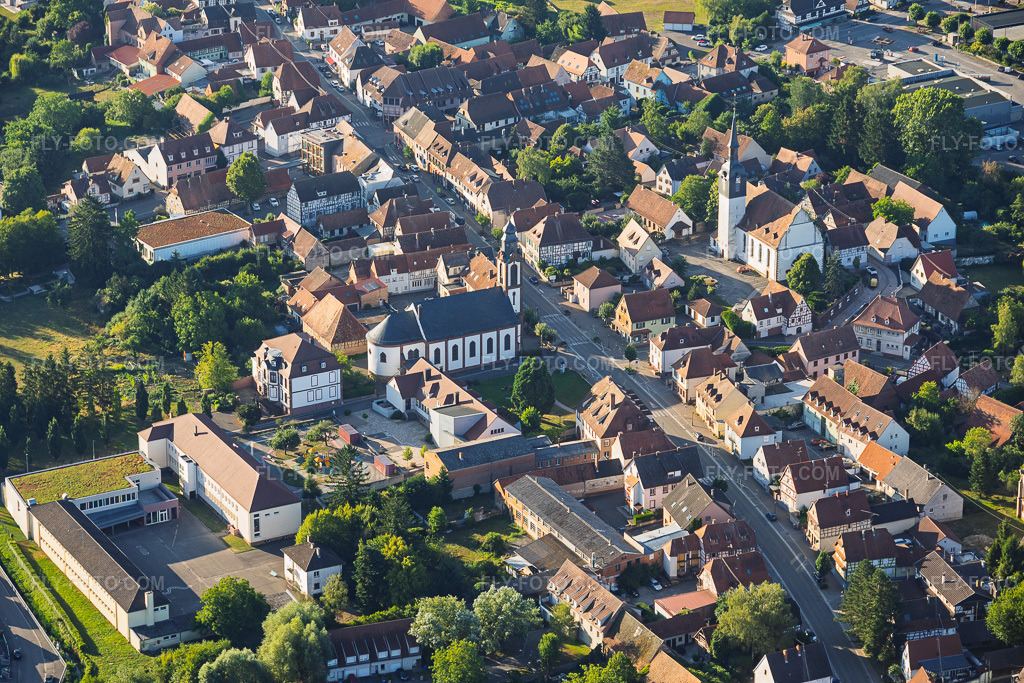Aerial view: Town hall/primary school, Saint-Pierre-Saint-Paul Church, and Protestant Church of Soultz-sous-Forêts in Soultz-sous-Forêts in the state Bas-Rhin, France. – Photo: IMG_158141.jpg taken on 07/25/2026 by Werner Riehm/FLY-FOTO.com – Resolution of the original: 6000 x 4000 px – PAROISSE-SSF.COM – la communauté protestante de Soultz s/s ForêtsLobsann et Retschwiller !