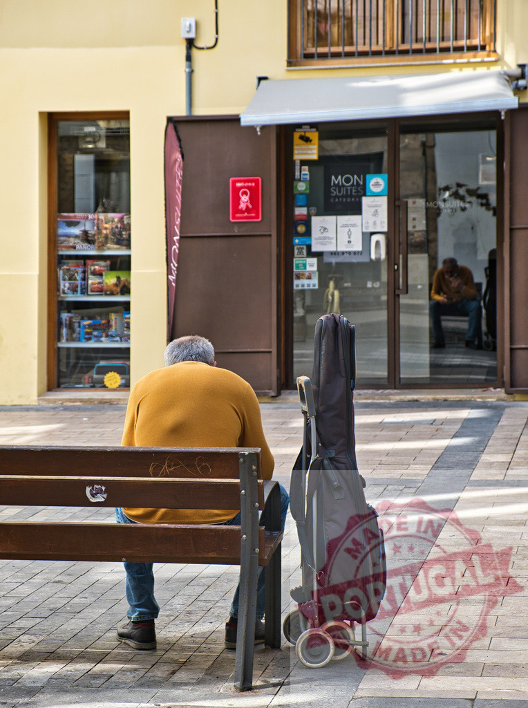 Street musician resting on bench with guitar | Street musician resting on a bench next to a guitar case, reflecting urban life and solitude - Realisiert mit Pictrs.com