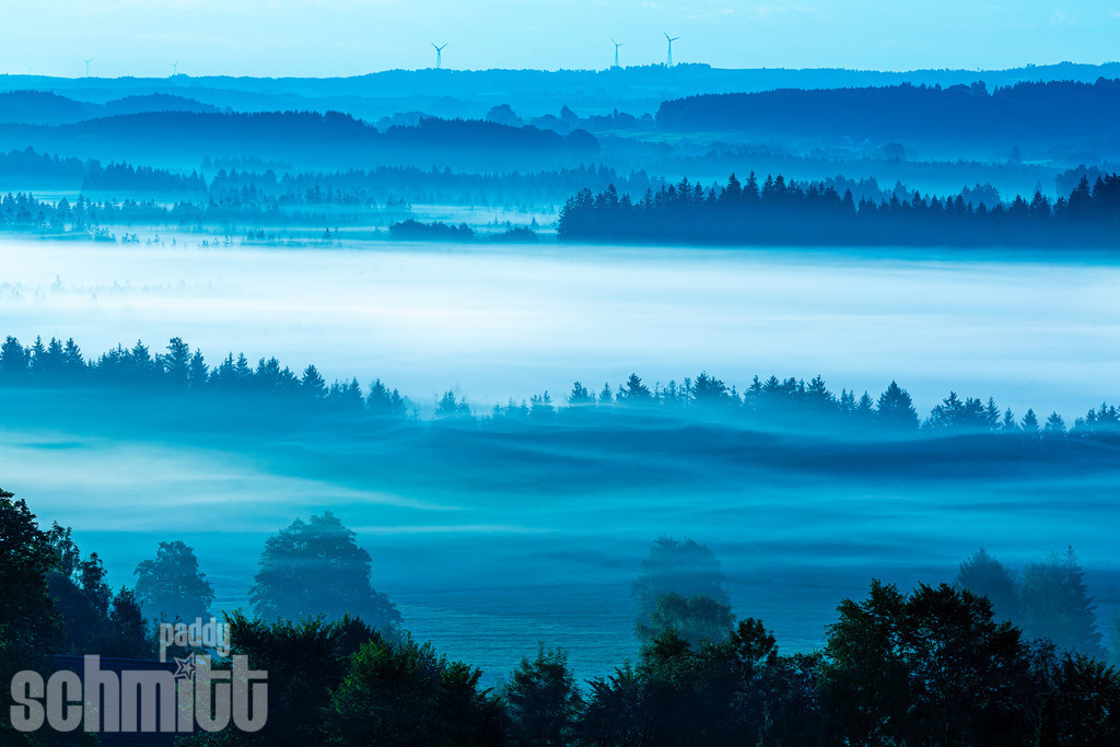 Blaue Stunde mit Morgennebel im Allgäu | Stimmungsvolle Blaue Stunde im Allgäu, während feiner Morgennebel über der Landschaft liegt und die ersten Lichtstimmungen des Tages sichtbar werden. Eine ruhige Aufnahme, die die besondere Atmosphäre eines frühen Herbstmorgens einfängt. - Realisiert mit Pictrs.com