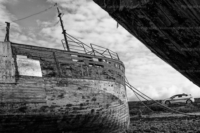 Verlassene Boote an der Küste | Schwarzweißaufnahme alter, verwitterter Boote an einer rauen Küste. Die Spuren von Zeit, Wind und Meer, die harte Struktur des Holzes und die grafische Bildgestaltung erzeugen eine stille, dokumentarische und maritime Atmosphäre. - Realisiert mit Pictrs.com