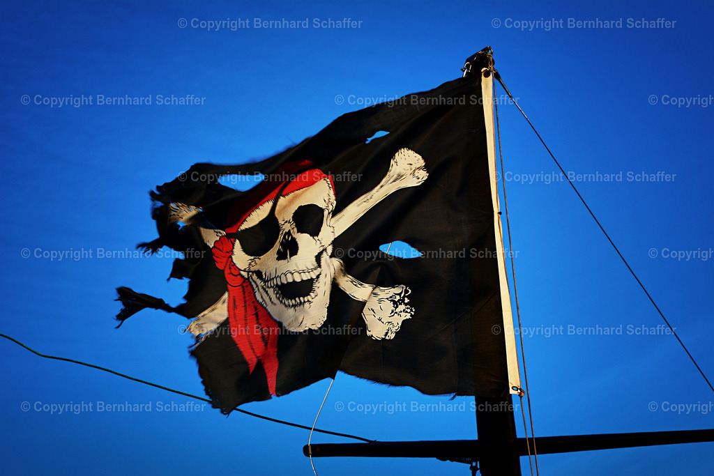 Jolly Roger | Piratenflagge Jolly Roger weht an einem Mast im Wind am Himmel. - Realisiert mit Pictrs.com