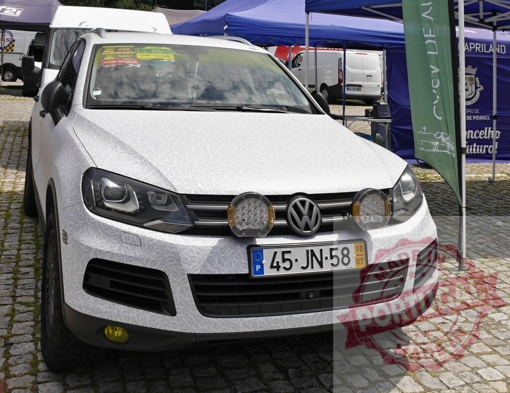 Custom Volkswagen Touareg SUV exhibiting rally lights at car event | Volkswagen Touareg SUV with custom textured wrap and rally lights parked on cobblestone - Realisiert mit Pictrs.com