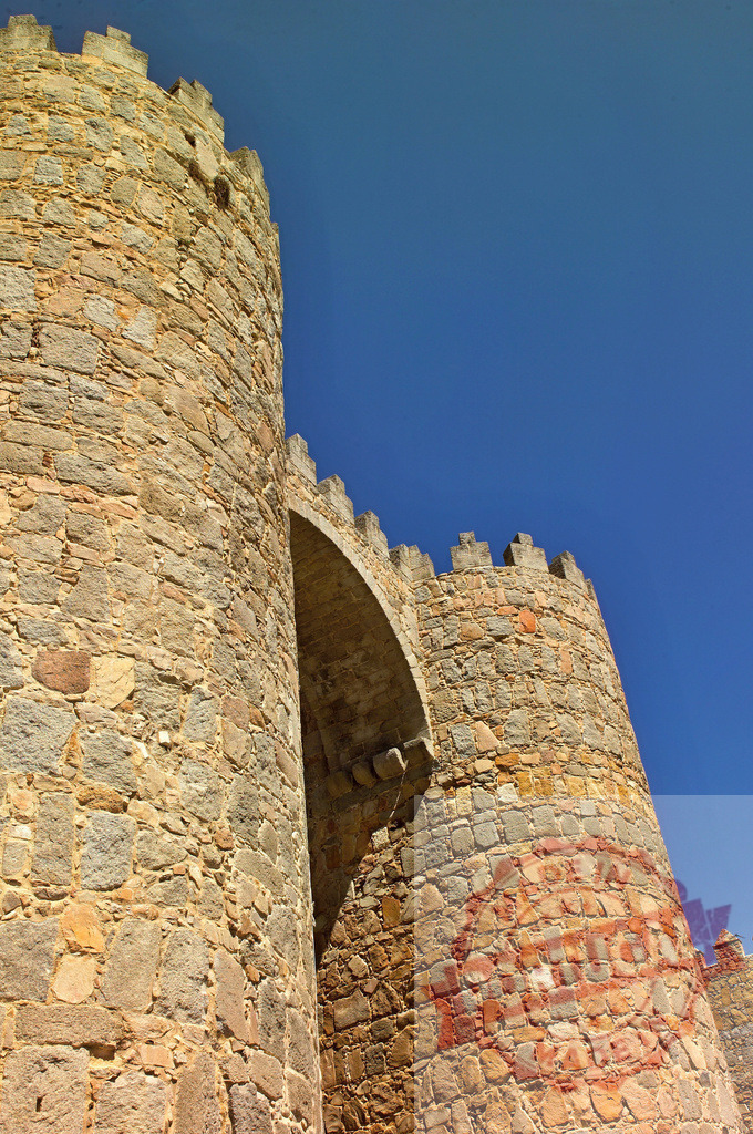 Ávila medieval city wall towers reaching blue sky. Spain - Avila | Ancient stone walls and defensive towers of Ávila, Spain against a clear blue sky - Realized with Pictrs.com