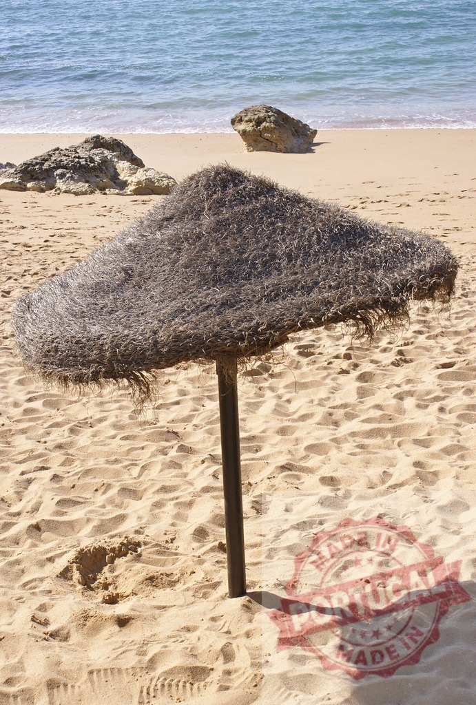 Thatched umbrella standing on a sandy beach | Thatched umbrella providing shade on a sun-drenched sandy beach with ocean waves - Realisiert mit Pictrs.com