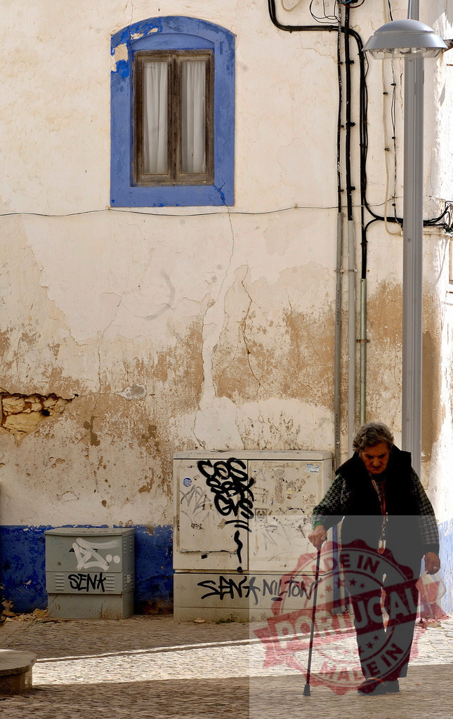 Elderly woman walking with stick in old European street | Elderly woman walking on a street with a walking stick in front of a rustic weathered wall - Realized with Pictrs.com