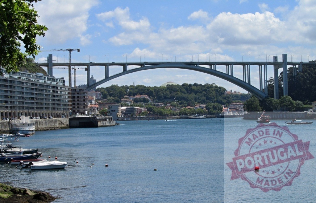 Ponte da Arrábida spanning Douro River in Porto, Portugal | Arrábida bridge crossing the tranquil Douro River with boats and city buildings under a clear sky - Realized with Pictrs.com