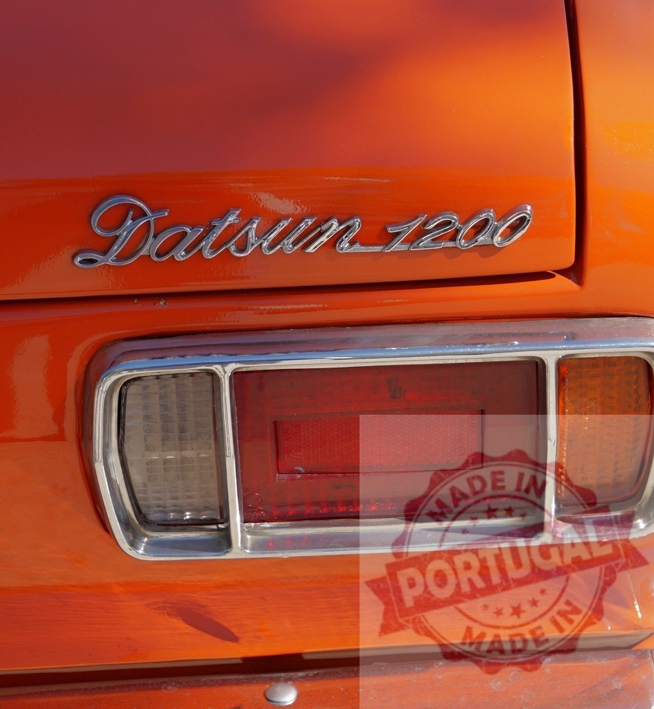 Datsun 1200 vintage car trunk detail showing chrome badge | Orange Datsun 1200 classic automobile rear showing chrome badge and taillight - Realisiert mit Pictrs.com