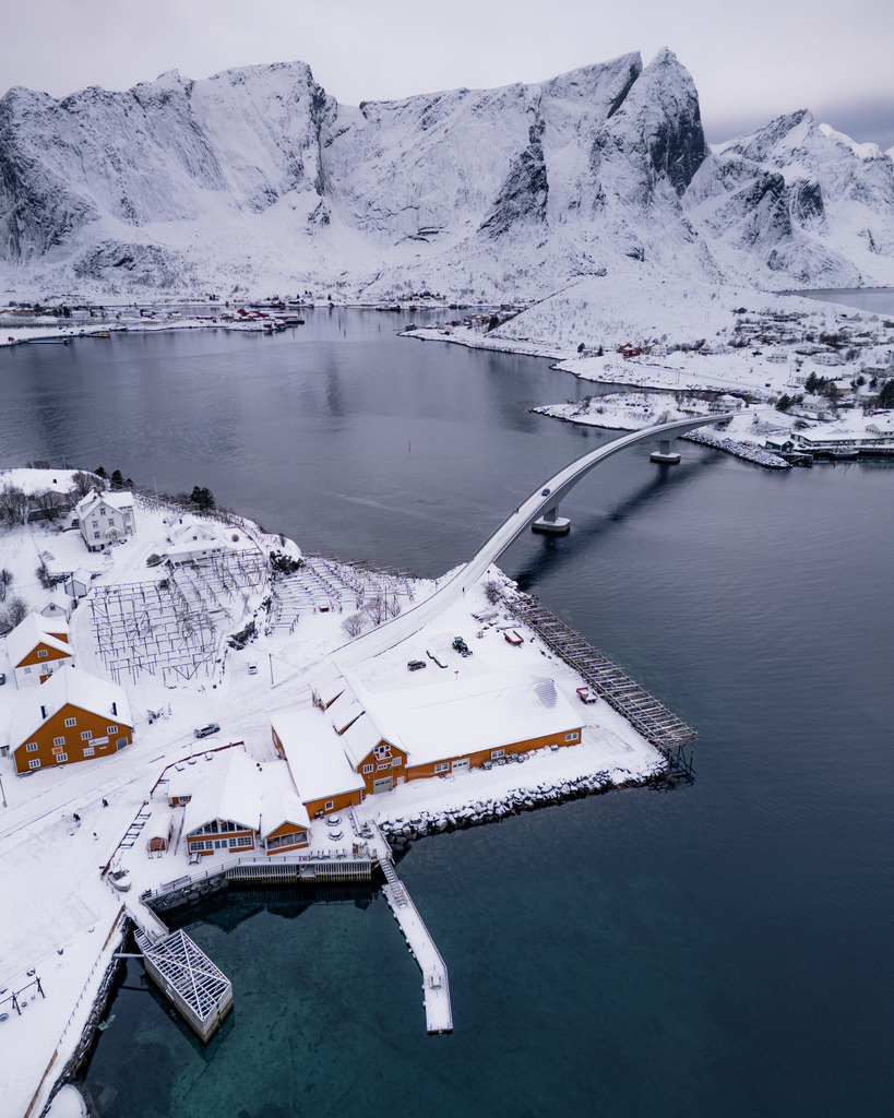 Winterlandschaft mit Brücke in Nordnorwegen | Eine Brücke verbindet die verschneite Küstenlandschaft mit einem kleinen norwegischen Ort. Die erhöhte Perspektive zeigt das Zusammenspiel aus Meer, Bergen, Straßen und winterlicher Architektur. - Realisiert mit Pictrs.com
