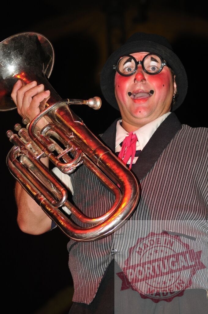 Clown performing music playing euphonium on stage | Clown with makeup and costume holding a euphonium during a performance - Realized with Pictrs.com