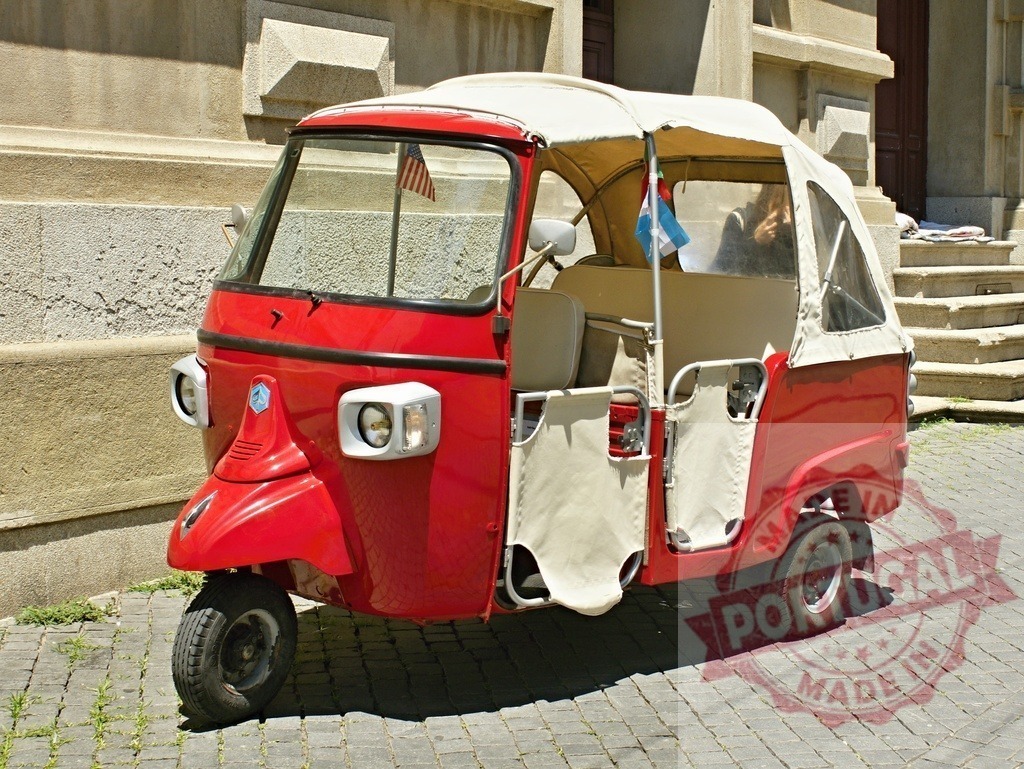 Red Piaggio Ape Calessino parked on cobblestone street | Red Piaggio Ape three-wheeled auto rickshaw parked on a sunny cobblestone street - Realized with Pictrs.com