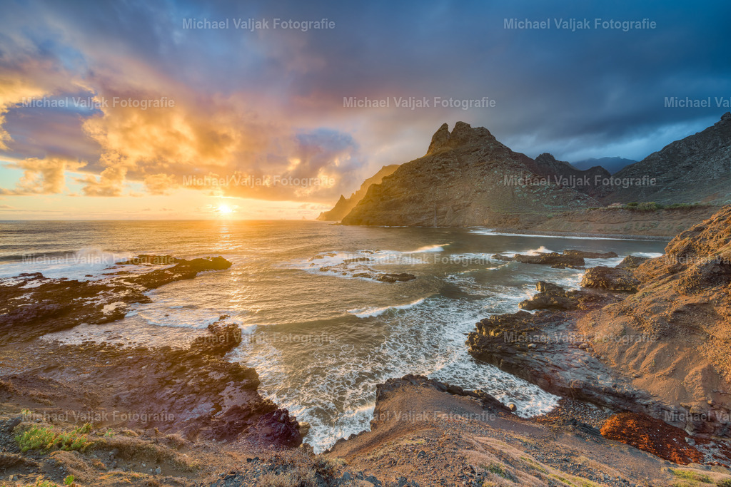 Punta del Hidalgo bei Sonnenaufgang | Punta del Hidalgo auf Teneriffa bietet bei Sonnenaufgang ein spektakuläres Naturschauspiel. Die ersten Sonnenstrahlen erleuchten die dramatische Küstenlandschaft und tauchen die Wellen des Atlantiks in ein warmes Licht. Dieser Ort ist bekannt für seine atemberaubenden Aussichten und die Ruhe, die man dort in den frühen Morgenstunden finden kann. Es ist ein perfekter Ort für Fotografen und Naturliebhaber, um die Schönheit der Natur in vollen Zügen zu genießen. - Realisiert mit Pictrs.com