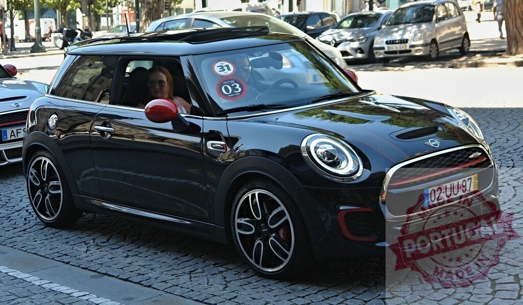 Woman driving Mini Cooper on cobblestone street | Black Mini Cooper with red accents being driven by a woman on a cobblestone street - Realized with Pictrs.com