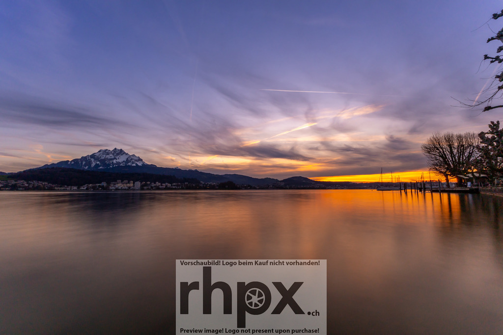 Sonnenuntergang am Vierwaldstättersee mit Pilatus | Der Pilatus im Abendlicht – die Sonne versinkt hinter den Bergen und färbt Himmel und Wasser in warme Gold- und Violetttöne. Der Vierwaldstättersee spiegelt die Ruhe und Schönheit der Zentralschweiz in perfekter Harmonie. - Realisiert mit Pictrs.com