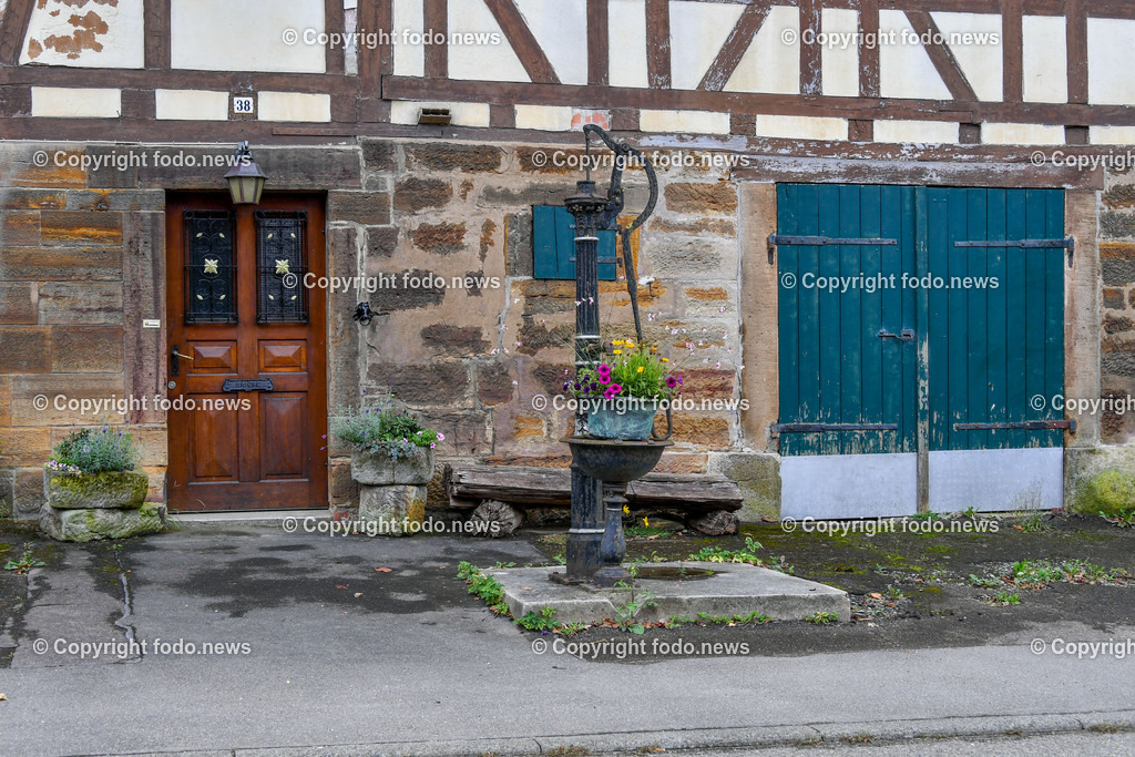 Deutschland_ Baden-Wuerttemberg_ Weilheim an der Teck_ 13.09.2025-10 | 13.09.2025, Deutschland, GER, Baden-Wuerttemberg, Weilheim an der Teck am Fuße der Schwaebischen Alb, im Bild Themenbild, Fachwerkhaus, alte Wasserpumpe, Blumenkuebel, Holztuer, blaue Doppeltuer, Steinmauer, Pflaster, laendlich, Garten, rustikal, Pflanzen, Blueten, Vintage, Außenbereich, Sitzbank, Feature, Symbolbild