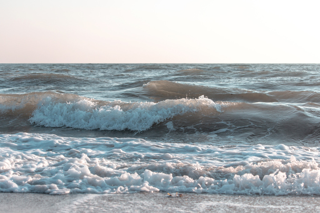 Wandbild: Wellen im Morgenrot | Dieses Wandbild im Querformat zeigt Wellen am Meer im Morgenrot. Dabei wirken die Wellen des Meers nicht nur blau, sondern auch beige, grau und braun. Der Himmel leuchtet in weiß und rotorange. Dadurch ergibt sich eine bezaubernde maritime Morgenstimmung die einen fast schon an einen Sepiaton erinnert. Holen Sie sich diese schöne maritime Morgenstimmung auf Leinwand, Aluminium-Platte oder als Glasbild. Ideal fürs Wohnzimmer, Schlafzimmer, Küche, den Arbeitsplatz oder die Ferienwohnung. Die Wandbilder werden individuell für Sie in vielen Abmessungen produziert. - Realisiert mit Pictrs.com