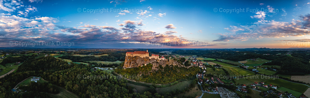 Drohnenpanorama der Riegersburg – Steiermark, Österreich | Die Riegersburg thront majestätisch auf ihrem markanten Felsen und blickt weit über das steirische Hügelland. Aus der Drohnenperspektive wirkt die Anlage besonders eindrucksvoll, eingerahmt von Feldern, Wäldern und einem dramatischen Himmel.