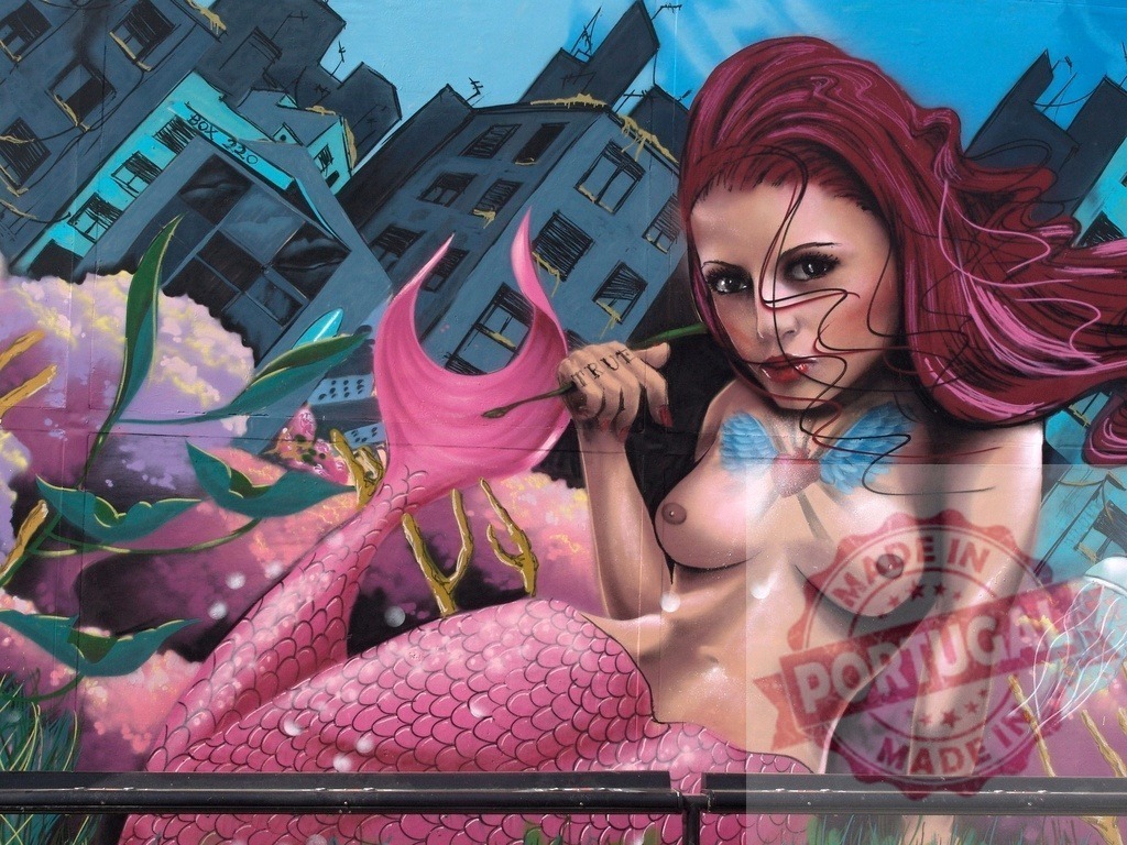 Mermaid with pink tail painting on a urban wall | Urban mermaid graffiti art on a wall with city buildings in the background - Realized with Pictrs.com
