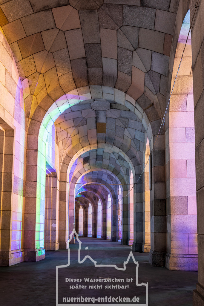 Hellerleuchteter Gang um die Kongresshalle | Der imposante Rundgang, um die alte Kongresshalle auf dem Reichsparteitagsgelände in Nürnberg bei Nacht. Durch das in der Nähe stattfindende Frühlingsvolksfest wird der Gang mit viel Licht und Farbe ausgefüllt. Normal gibt es in der Nacht keine Beleuchtung auf diesem Gelände. - Realisiert mit Pictrs.com