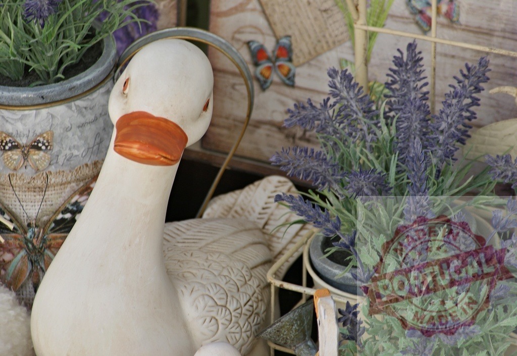 Goose figurine with lavender plants creating rustic farmhouse decor | Goose figurine creating a rustic farmhouse decoration with potted lavender plants and butterflies - Realized with Pictrs.com