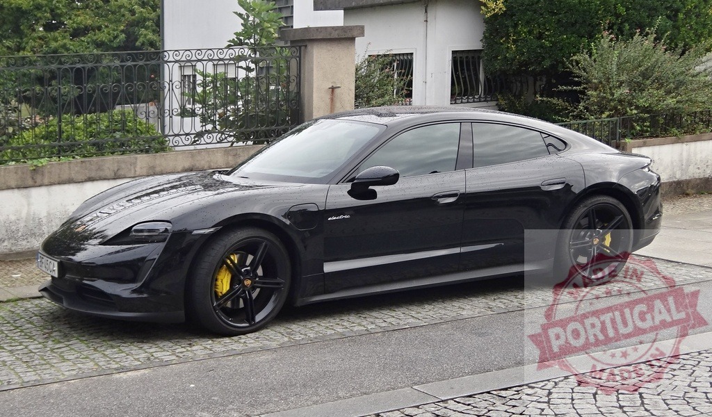 Black Porsche Taycan electric sedan parked on cobblestone street | Porsche Taycan electric car parked on a European street with yellow brake calipers - Realisiert mit Pictrs.com