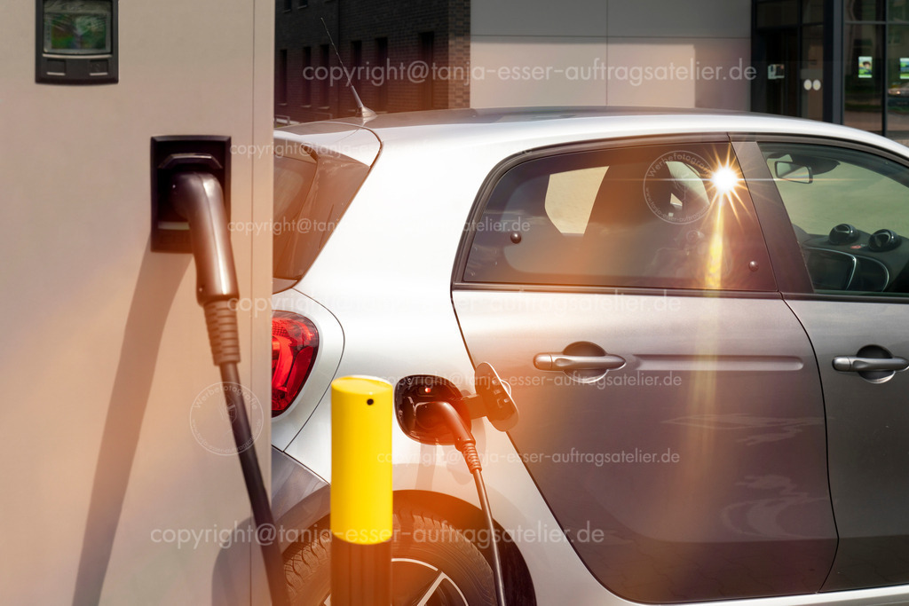 EAuto Ladestation2 D | Elektro Auto steht an einer Ladestation und wird aufgeladen. Die Sonne erzeugt Lens Flares. Brilon, Deutschland.                                