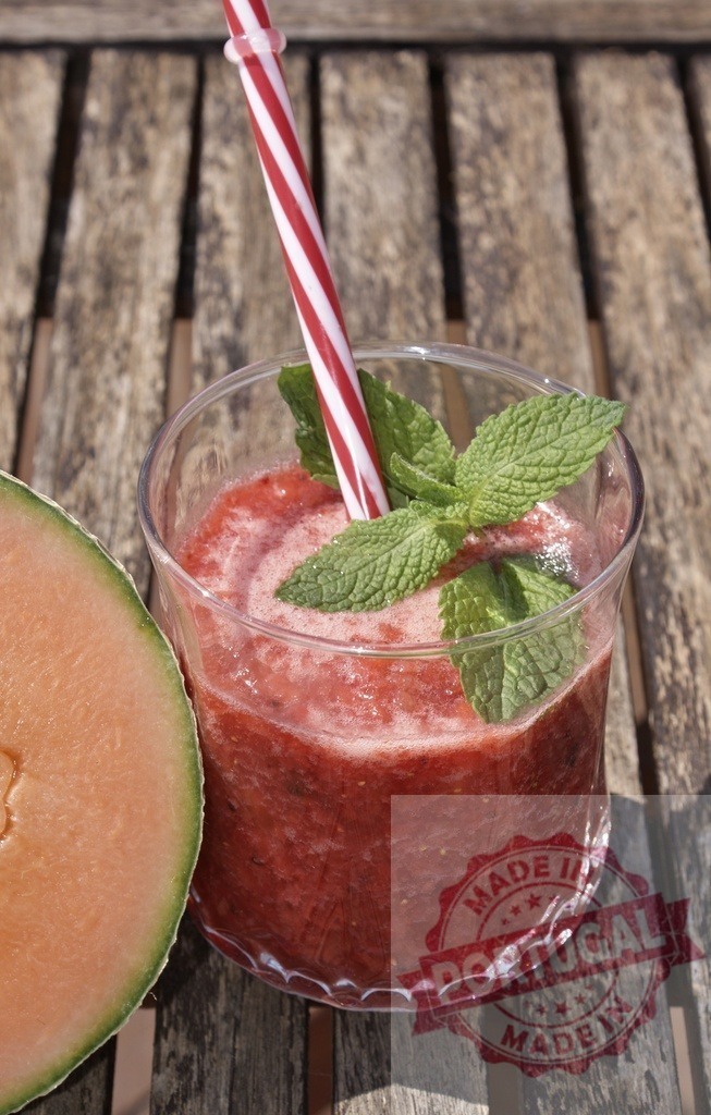 Melon and strawberry healthy refreshing summer smoothie drink | Melon and strawberry smoothie with mint and a straw on a wooden table - Realisiert mit Pictrs.com
