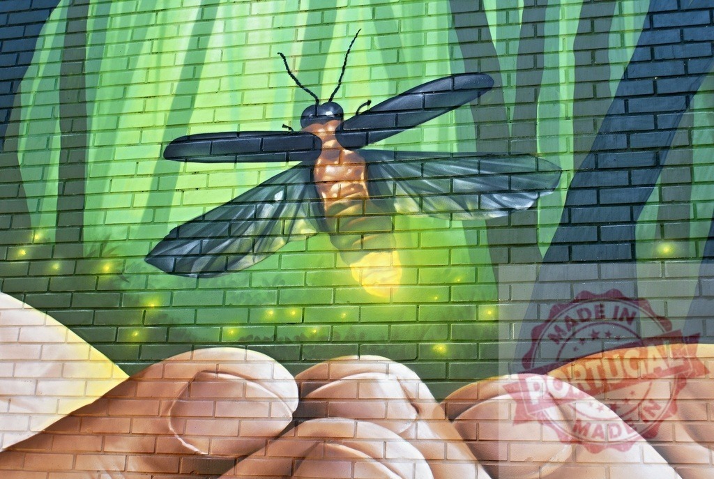 Firefly street art mural on brick wall with hands | Firefly glowing above hands in a green forest mural on a brick wall - Realized with Pictrs.com