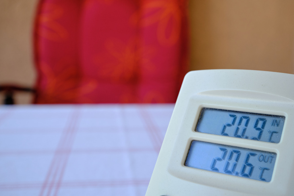 Blick auf Thermometer mit Tisch und Stuhl | Wien, Austria - May 29, 2025: Blick auf ein Thermometer mit Tisch und rotem Stuhl auf dem Balkon. - Realisiert mit Pictrs.com