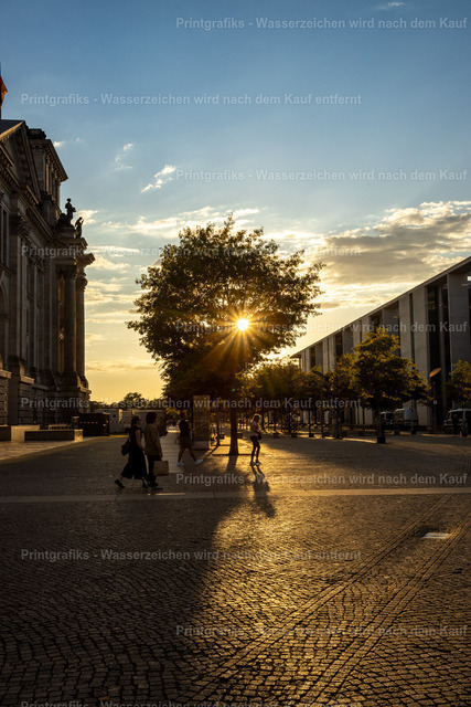 Abendlicht am Reichstag in Berlin | Stimmungsvolle Stadtszene in Berlin mit tief stehender Sonne, Baum-Silhouette und warmem Licht auf dem Pflaster. Die Mischung aus historischer Architektur, moderner Stadtlandschaft und urbanem Abendlicht erzeugt eine ruhige, lebendige Atmosphäre. - Realisiert mit Pictrs.com