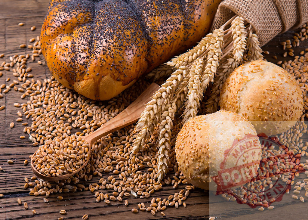 Rustic bakery products with wheat grains and poppy seeds | Freshly baked bread and rolls on a wooden table with scattered wheat and ears - Realized with Pictrs.com