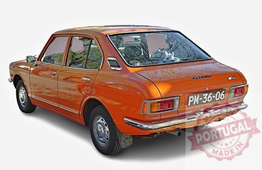 Orange Toyota Corolla parked, showing its rear, reflecting trees in the back window | Classic orange Toyota Corolla parked, reflecting trees in the back window, showcasing its vintage charm - Realisiert mit Pictrs.com