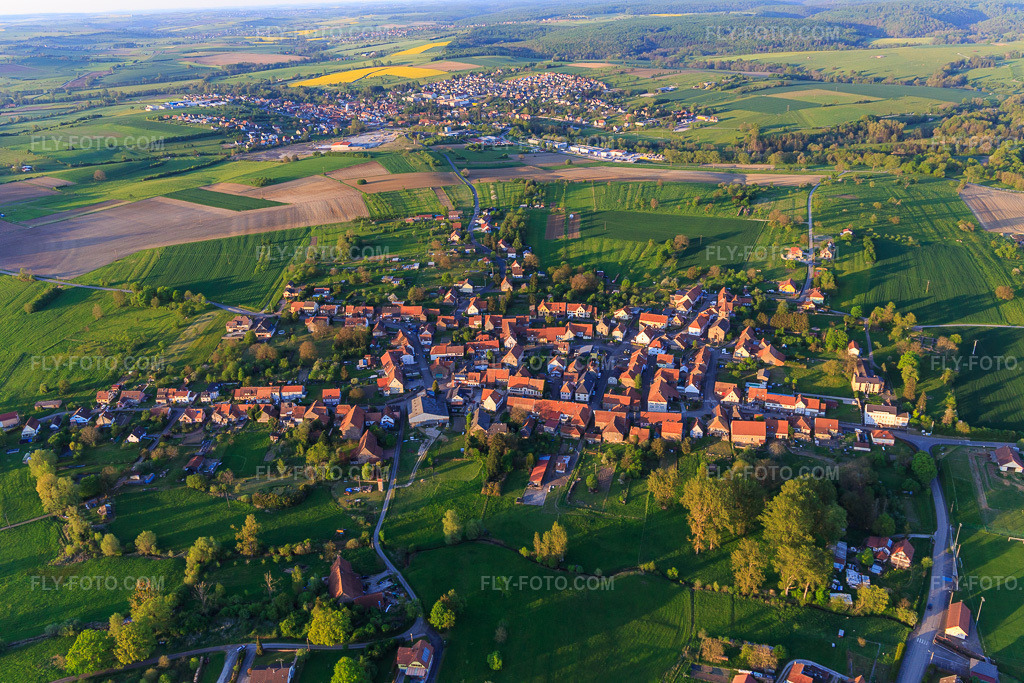 Aerial view: Village view from the west in Mackwiller in the state Bas-Rhin, France. – Photo: IMG_145868.jpg taken on 04/30/2025 by Werner Riehm/FLY-FOTO.com – Resolution of the original: 5472 x 3648 px