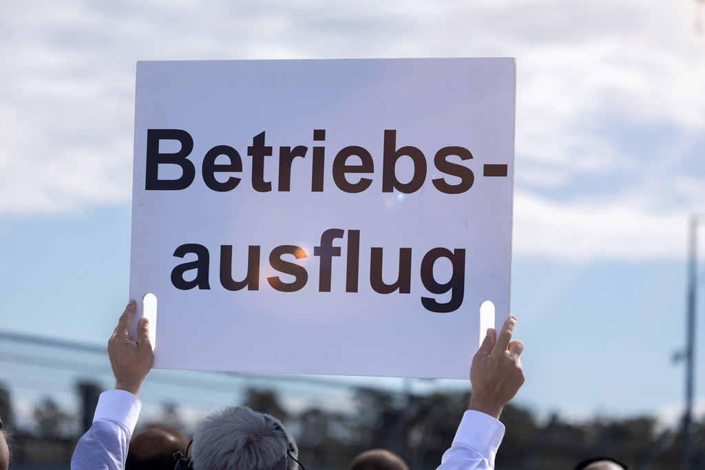 BETRIEBSAUSFLUG Schild | (Fotomontage) Ein Schild mit dem Text BETRIEBSAUSFLUG wird in die Höhe gehalten - Realisiert mit Pictrs.com