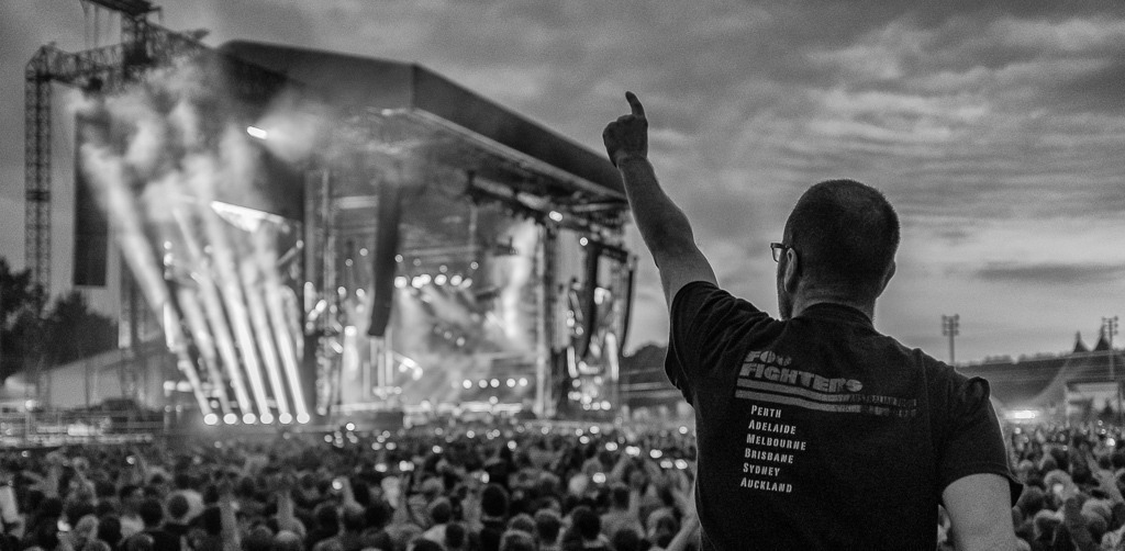 foo-fighters-2018-235 | Besucher beim Konzert der US-amerikanischen Rockband Foo Fighters auf der Trabrennbahn Hamburg-Bahrenfeld am 10. Juni 2018. Auf der Videowand ist der Bandgründer, Gitarrist und Sänger Dave Grohl zu sehen. - Realisiert mit Pictrs.com