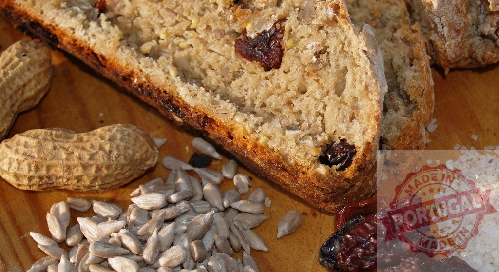 Slicing whole grain bread with seeds and fruits | Sliced whole grain bread with peanuts, sunflower seeds, raisins, and salt on a wooden board - Realisiert mit Pictrs.com
