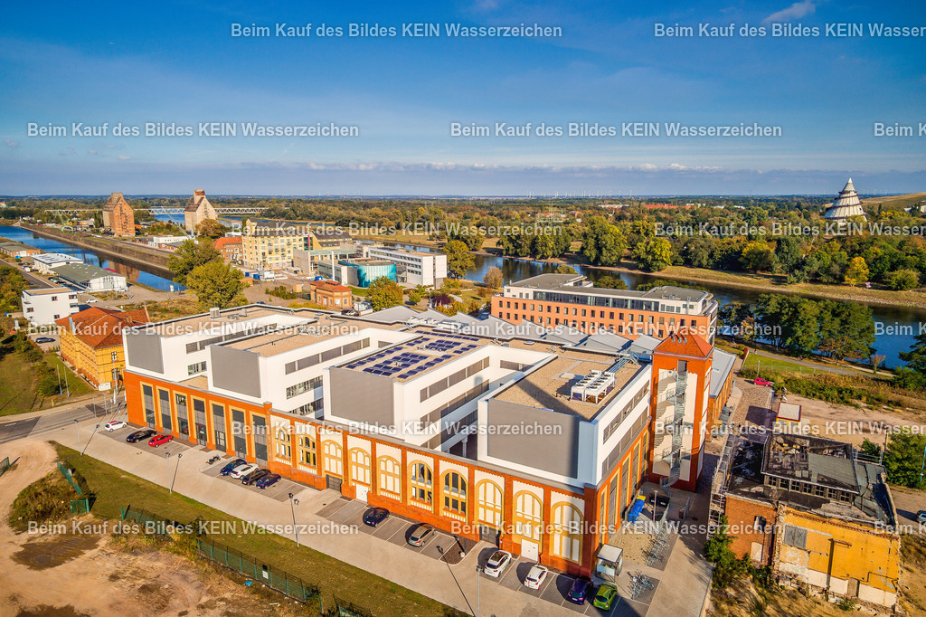 Magdeburg_Luftbild_Elbarkaden_Handelshafen_Wissenschaft_Elbe-0010 | Die Luftaufnahme aus der Drohne zeigt die Elbarkaden im Magdeburger Wissenschaftshafen, ein markantes Ensemble im ehemaligen Handelshafen. Die historische Backsteinarchitektur der früheren Industriegebäude wurde mit modernen Gebäudeteilen verbunden und prägt heute das Erscheinungsbild des Standorts. Im Hintergrund sind der Elbe-Havel-Kanal, die Elbe und weitere markante Bauwerke des Wissenschaftshafens zu sehen. Die Aufnahme zeigt eindrucksvoll das Zusammenspiel von historischer Bausubstanz, moderner Architektur und der Lage am Wasser. Die Aufnahme ist Teil des Mitteldeutschen Bildarchivs von Luftbildfotograf Steffen Lehmann. - Realisiert mit Pictrs.com