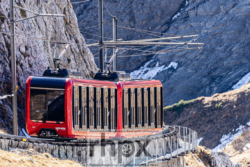 Pilatusbahn am Fels | Technik. Fels. Innovation.Die steilste Zahnradbahn der Welt schraubt sich unaufhaltsam durch die massive Felslandschaft am Pilatus. Das leuchtende Rot der modernen Kabine bildet einen faszinierenden Kontrast zum rauen, grauen Stein des Bergmassivs.Wähle unter "Produktauswahl" dein Wunschformat: Vom klassischen Wandbild über Puzzle &amp; Tassen bis zum digitalen Download (z.B. als Handy-Hintergrund). - Realisiert mit Pictrs.com