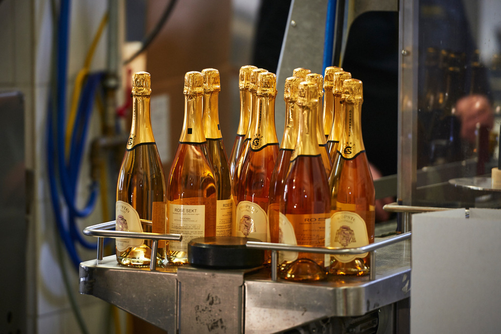 Sektkellerei Szigeti | Gols, Austria - February 19, 2018: Sektkellerei Szigeti; Mitarbeiter am Arbeitsplatz mit schwarzer Jacke und goldener Szigeti Aufschrift. - Realisiert mit Pictrs.com